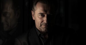 Portrait illustrating malignant narcissist manipulation tactics, with one side of the man’s face lit and the other concealed in shadow.